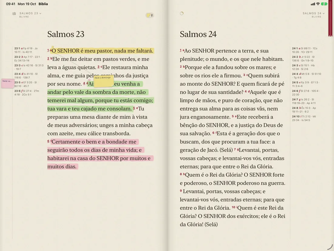 An iPad held sideways, with the Bible open in two pages, with marks and a sticky note
